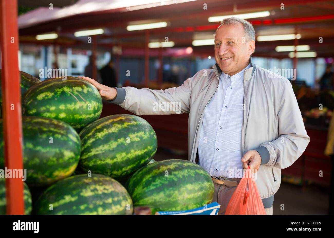 Uomo di mezza età che acquista cocomero Foto Stock