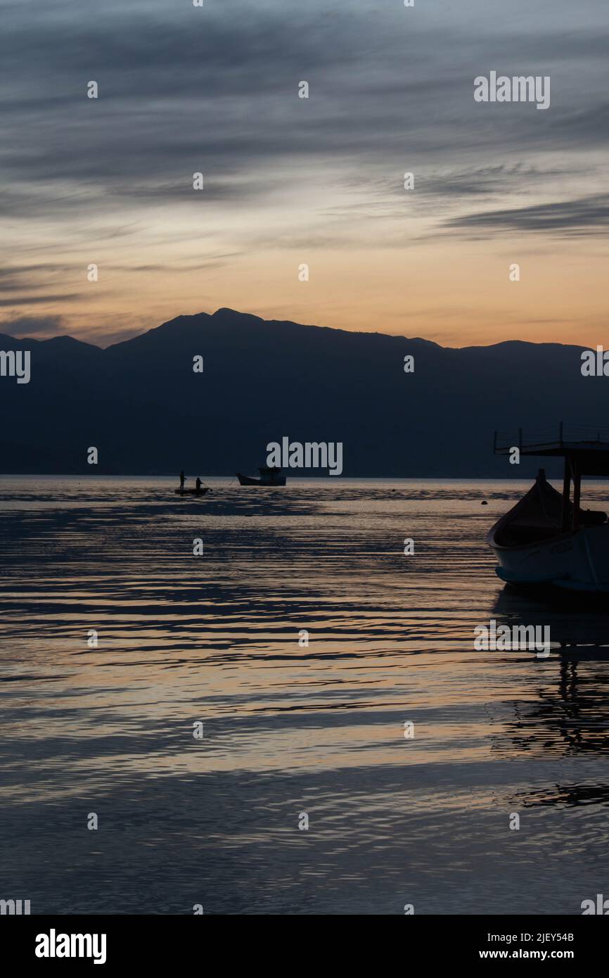 Incredibile tramonto sul mare, con piccole barche e le colline sullo sfondo, a Caieira da barra do sul, Foto Stock