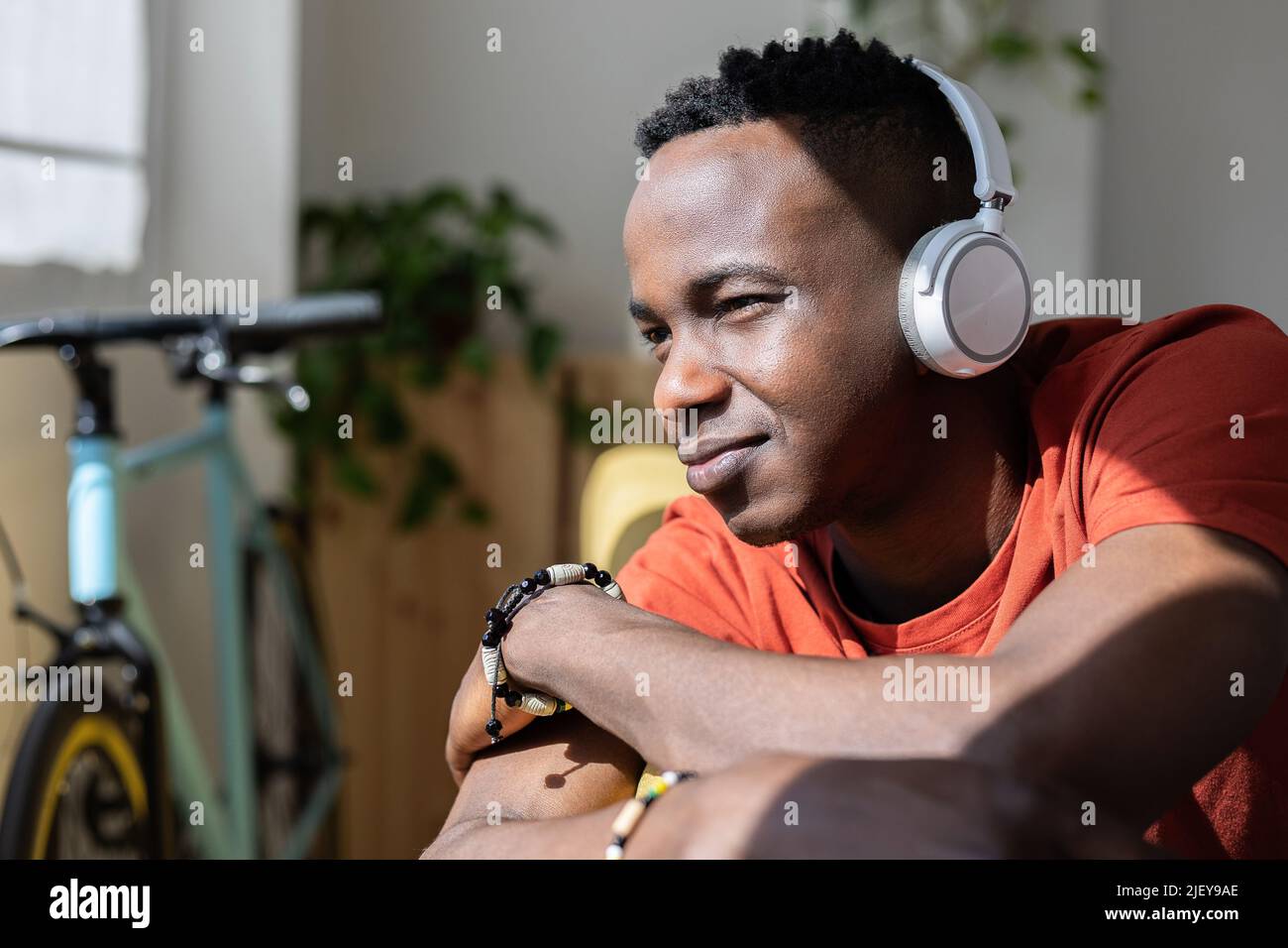Giovane africano che ascolta musica mentre si rilassa sul divano di casa Foto Stock