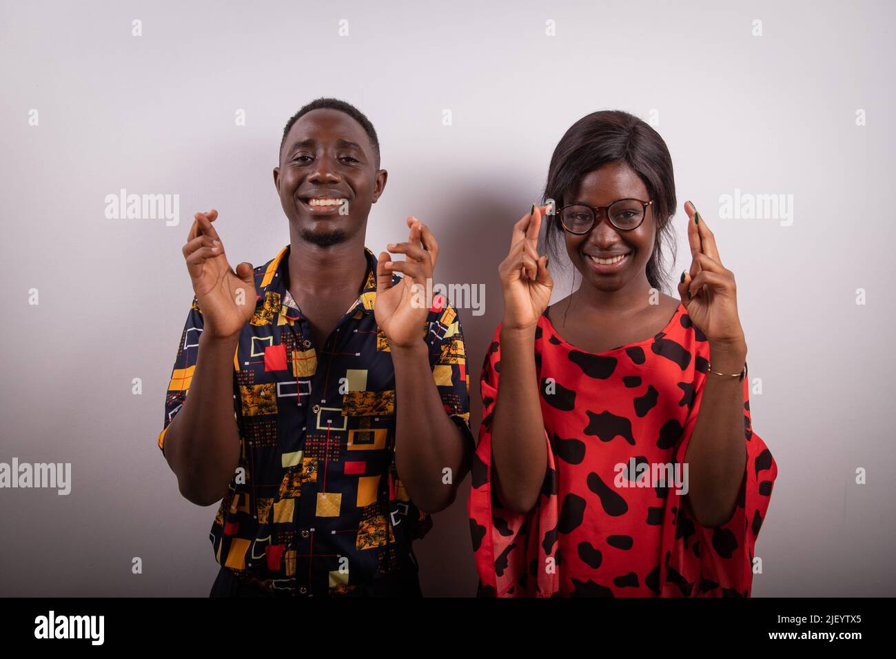 Un ragazzo e una ragazza africana con le dita incrociate, foto studio, concetto di buona fortuna e desiderio Foto Stock