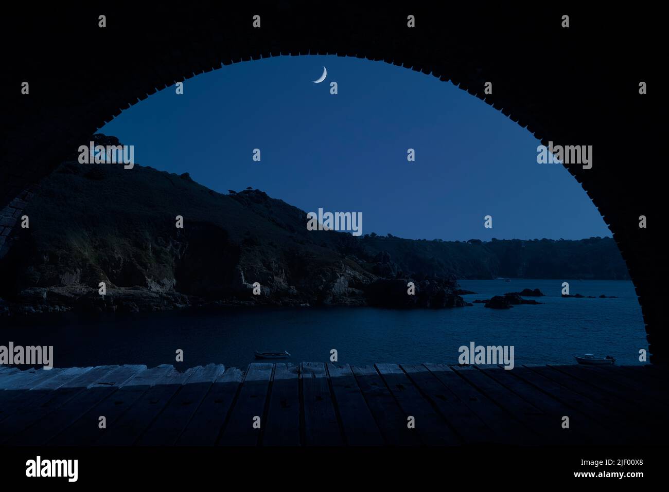 Quarto di luna sul porto di Saints Bay a Guernsey, un'isola della Manica Foto Stock