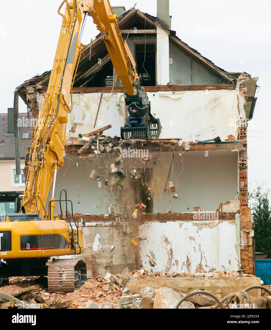 Escavatore per impieghi gravosi che demolisce un vecchio edificio residenziale Foto Stock