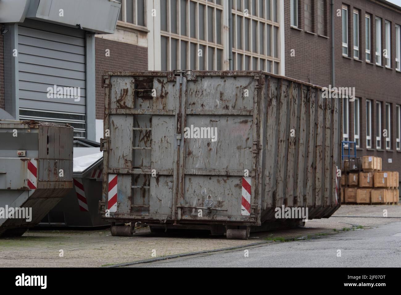 Grande contenitore grigio per rifiuti (dumpster) davanti a un edificio industriale Foto Stock