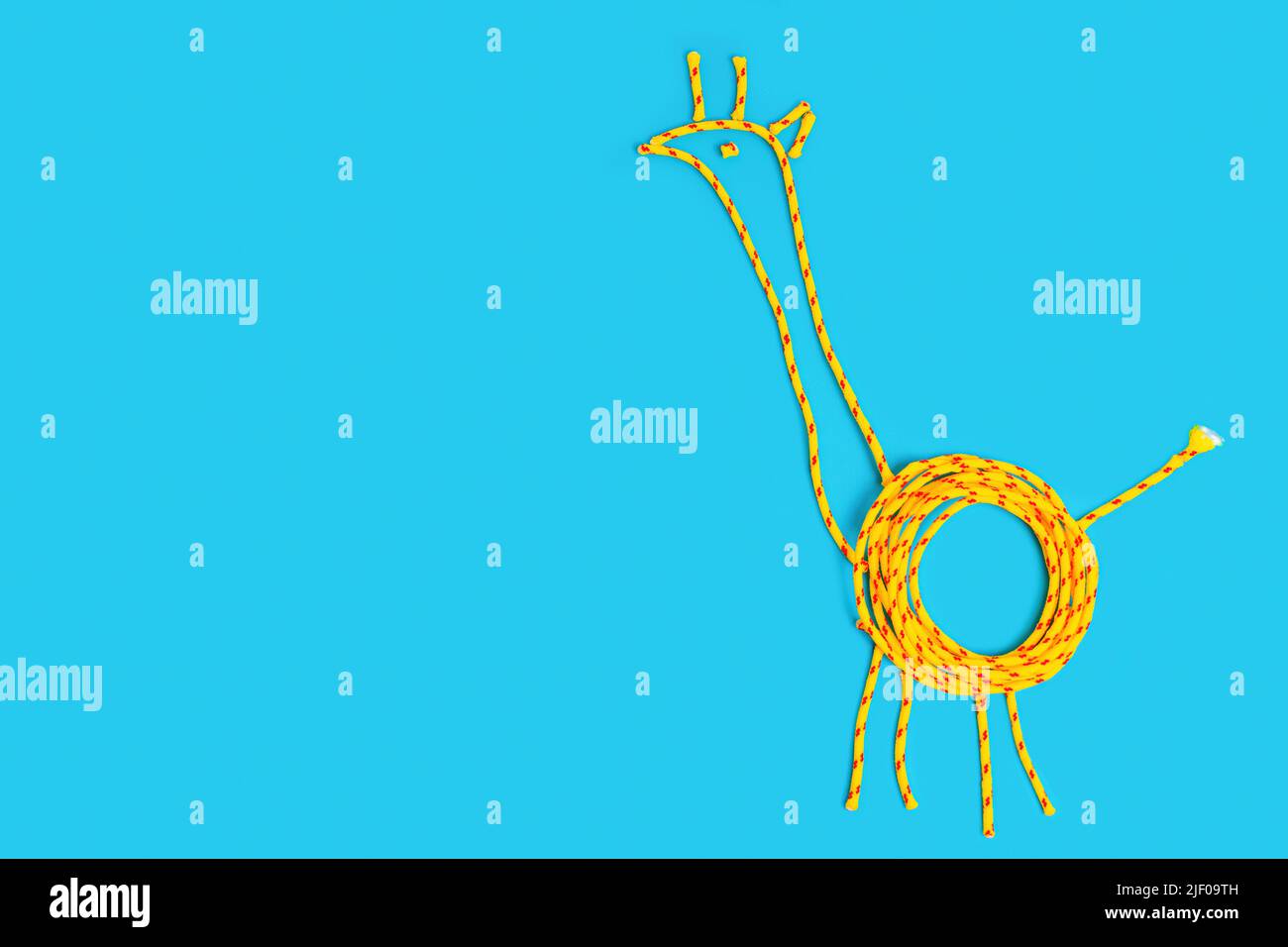 Forma giraffa realizzata in cordoncino intrecciato su sfondo blu con spazio copia. Foto Stock