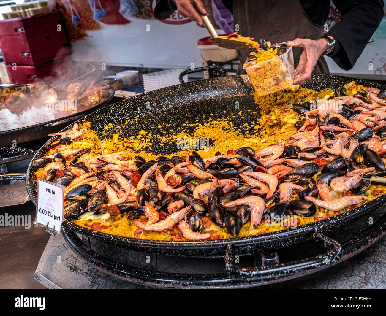Paella bancarella alimentare all'aperto con paellera piatto piatto piatto di metallo nel mercato alimentare a Moëlan sur Mer Bretagna Francia Foto Stock