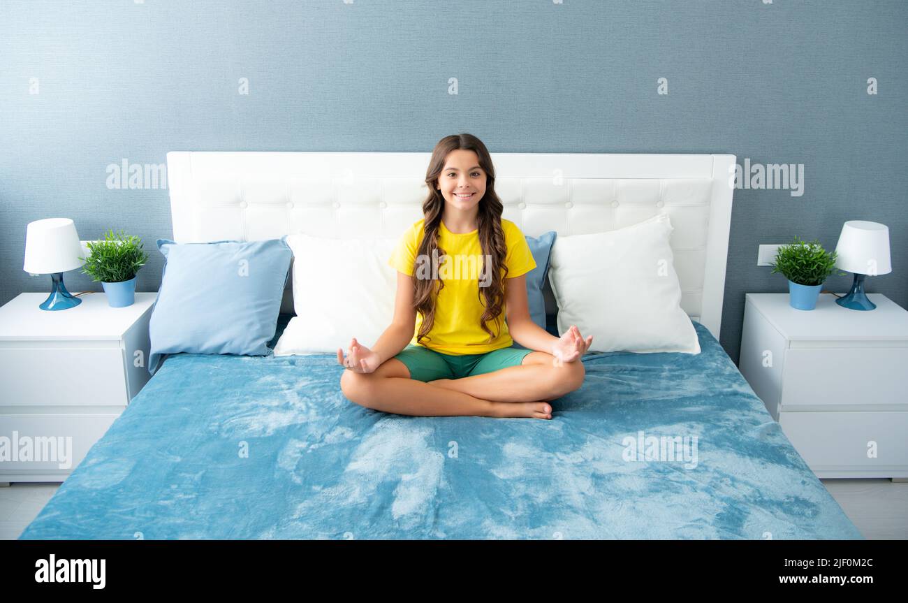 Bambino adolescente che pratica la meditazione in camera da letto. Meditazione mattutina a letto. Foto Stock