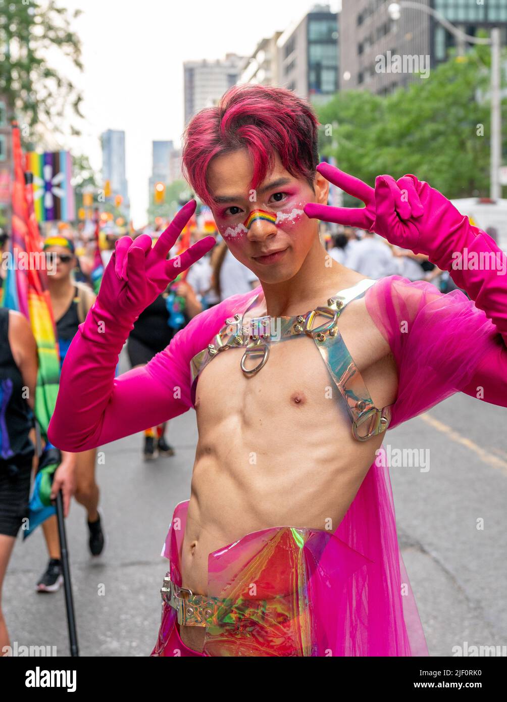 Colpo medio di un giovane uomo che indossa palco marciando su misura di fronte a un gruppo durante la Pride Parade Foto Stock