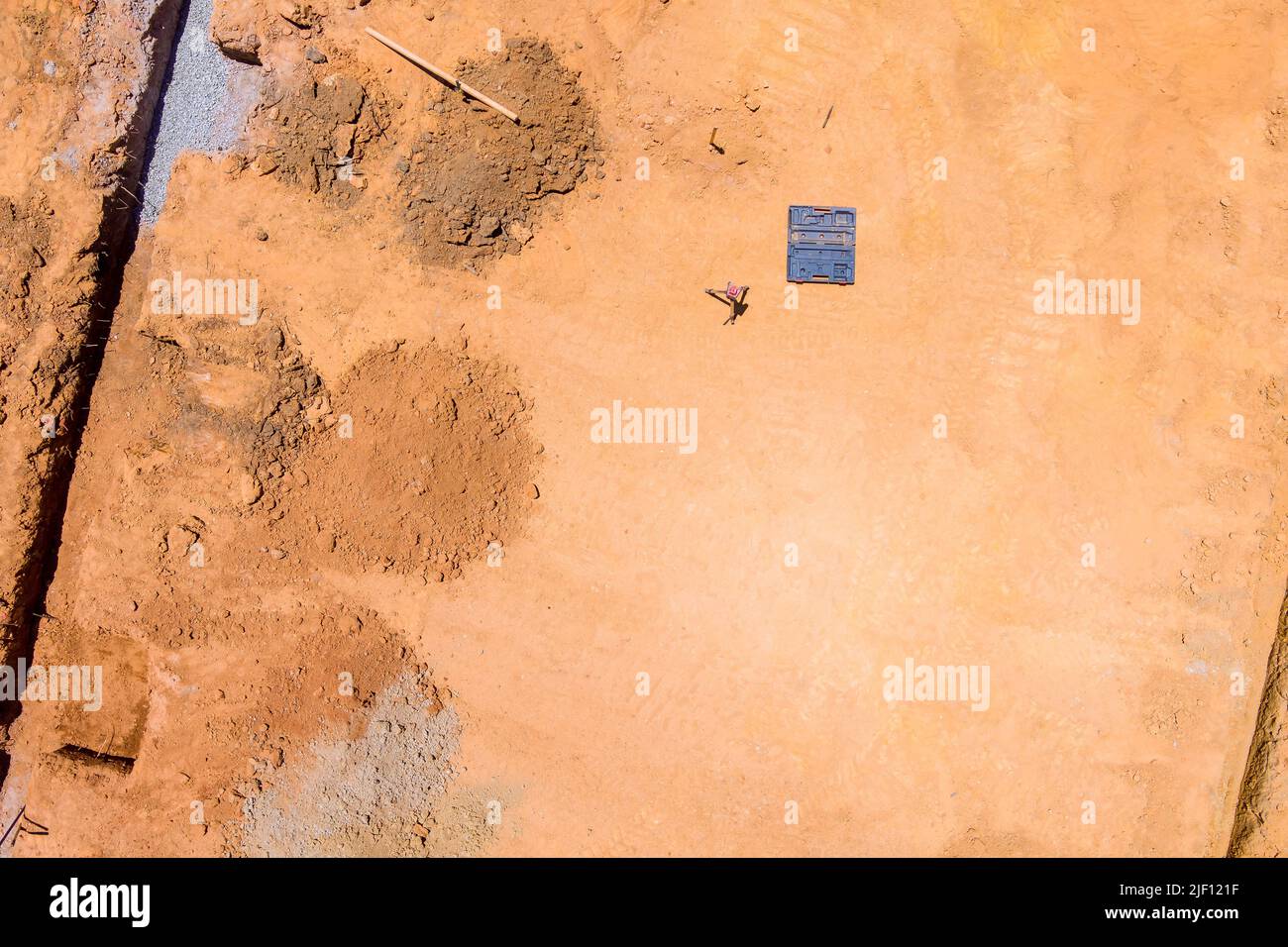 Un cantiere con una trincea scavata sotto una fondazione in calcestruzzo Foto Stock