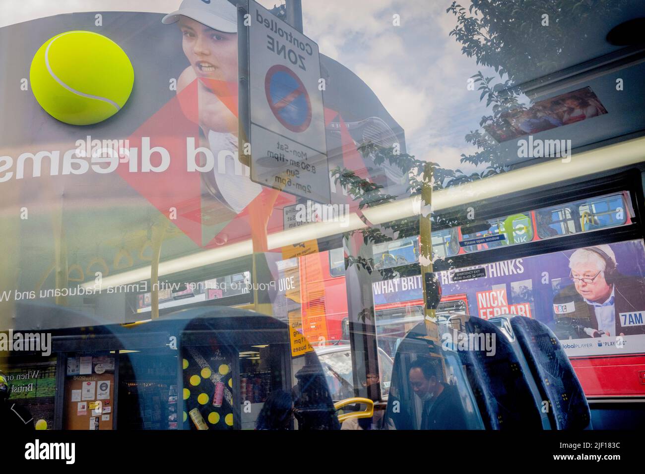 Riflesso nella finestra di un autobus, giocatore di tennis britannico, Emma Raducanu appare su un tabellone gigante nel centro di Wimbledon, nella seconda giornata di competizione durante i campionati della Wimbledon Lawn Tennis Association, il 28th giugno 2022, a Londra, Inghilterra. Foto Stock