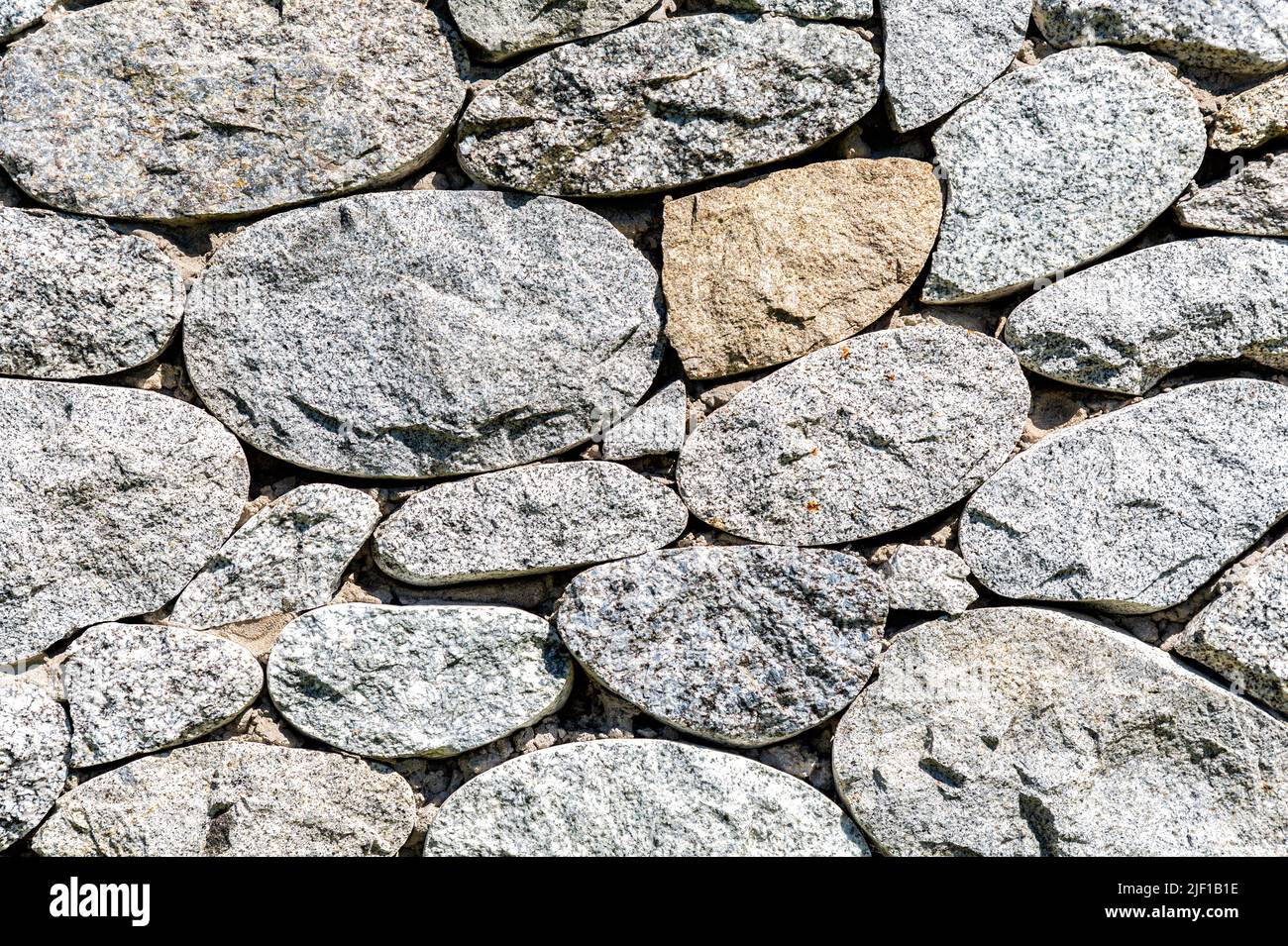Parete di pietra ruvida come texture di sfondo creativa. Pietre naturali muratura con cuciture irregolari. Sfondo muro di pietra Foto Stock