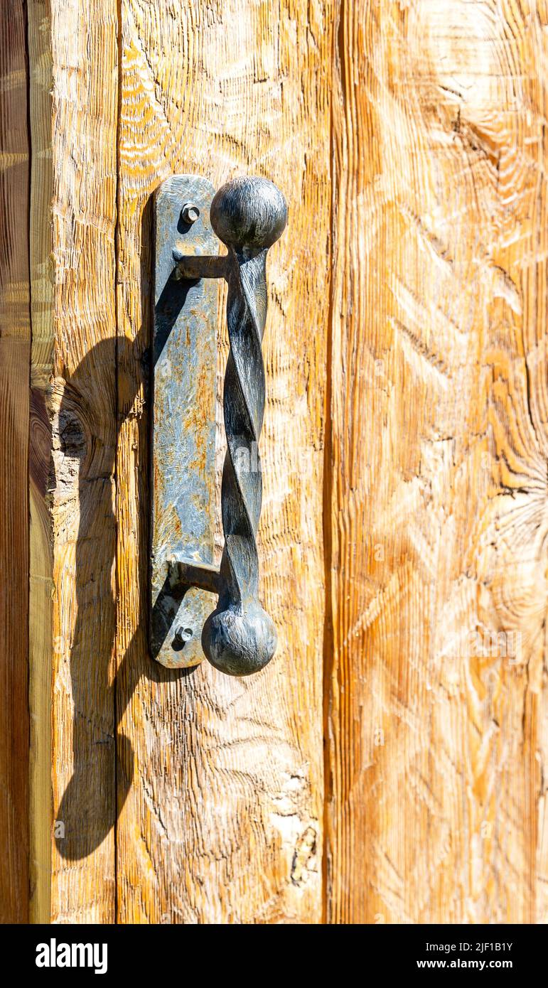 Maniglia della porta forgiata a mano sulla porta in legno da vicino Foto Stock