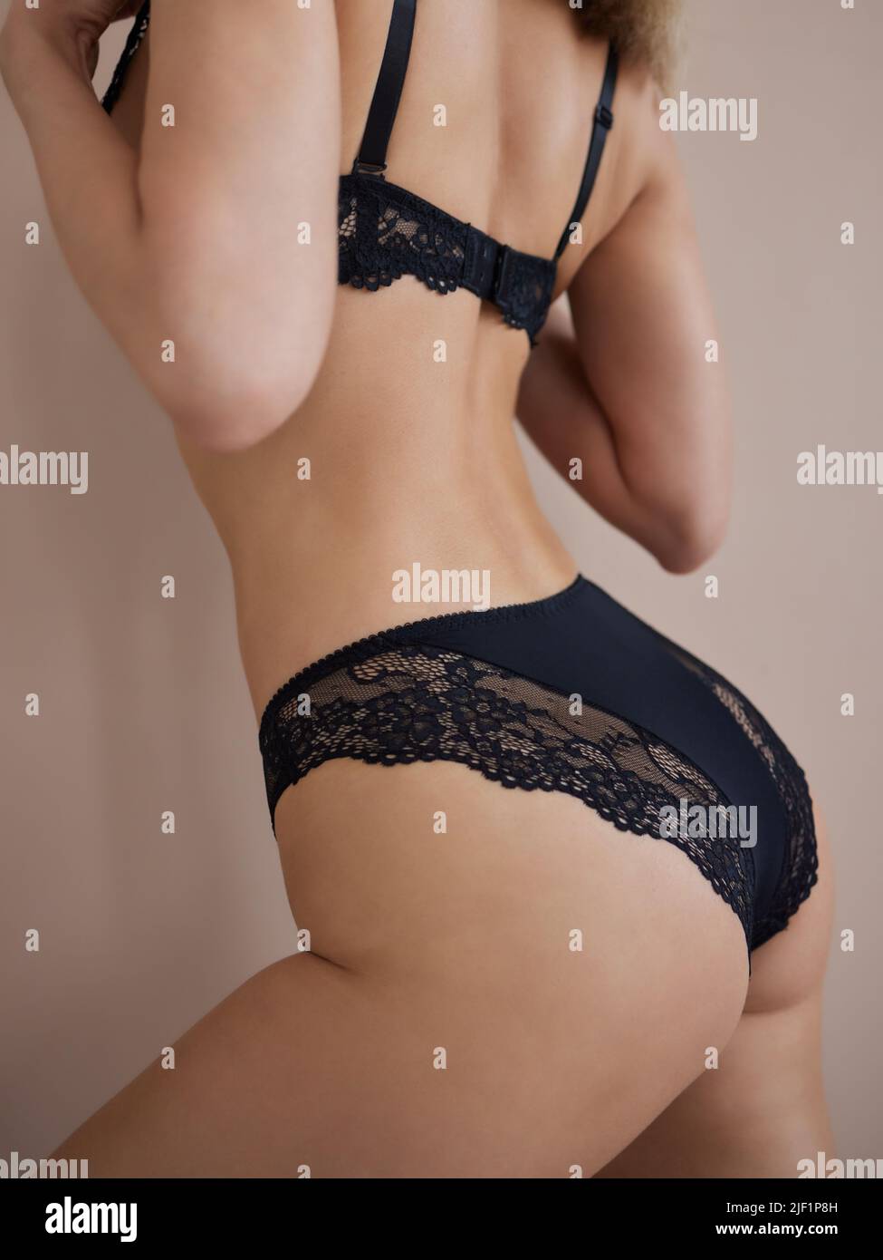 giovane donna in lingerie nero trasparente in posa sullo sfondo dello studio Foto Stock