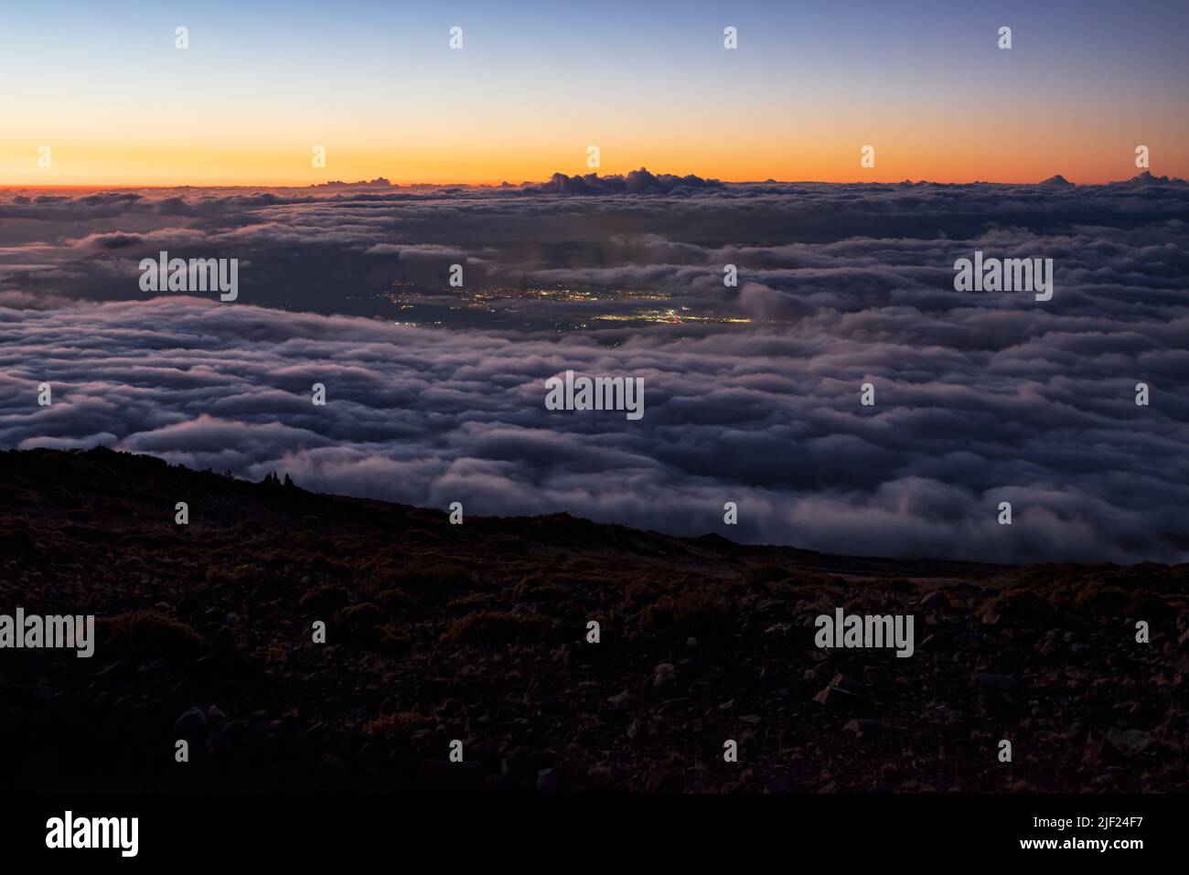 crepuscolo sopra le nuvole e le luci della città visibile al parco nazionale di haleakala maui hawaii Foto Stock