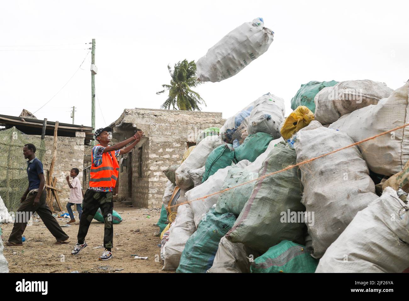 I membri di un gruppo comunitario per l'ambiente, Weka Lamu Safi (Keep Lamu Clean), accumulano sacchi di rifiuti plastici in un cantiere prima di essere trasportati all'officina dell'organizzazione FlipFlopi per il riciclaggio. Nel 2019 l'Organizzazione FlipFoppi costruisce una barca a vela quasi interamente da rifiuti di plastica riciclata raccolti dalle rive dell'Oceano Indiano. L'inquinamento da attività umane ha avuto un impatto negativo sugli oceani. Il presidente keniota Uhuru Kenyatta nel suo discorso durante la conferenza oceanica in corso a Lisbona, il Portogallo ha detto che l'inquinamento plastico sta falciando e contaminando almeno 700 specie Foto Stock