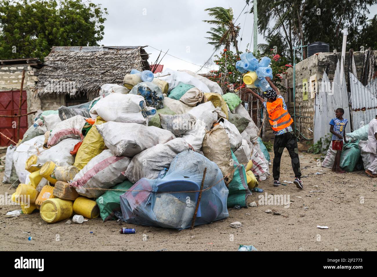 Un membro di un gruppo ambientale comunitario, Weka Lamu Safi (Keep Lamu Clean), accumula sacchi di rifiuti plastici in un cantiere prima di essere trasportato all'officina dell'organizzazione FlipFlipFlipFoppi per il riciclaggio. Nel 2019 l'Organizzazione FlipFoppi costruisce una barca a vela quasi interamente da rifiuti di plastica riciclata raccolti dalle rive dell'Oceano Indiano. L'inquinamento da attività umane ha avuto un impatto negativo sugli oceani. Il presidente keniota Uhuru Kenyatta nel suo discorso durante la conferenza oceanica in corso a Lisbona, il Portogallo ha detto che l'inquinamento plastico sta falciforme e contaminando almeno 700 speci Foto Stock