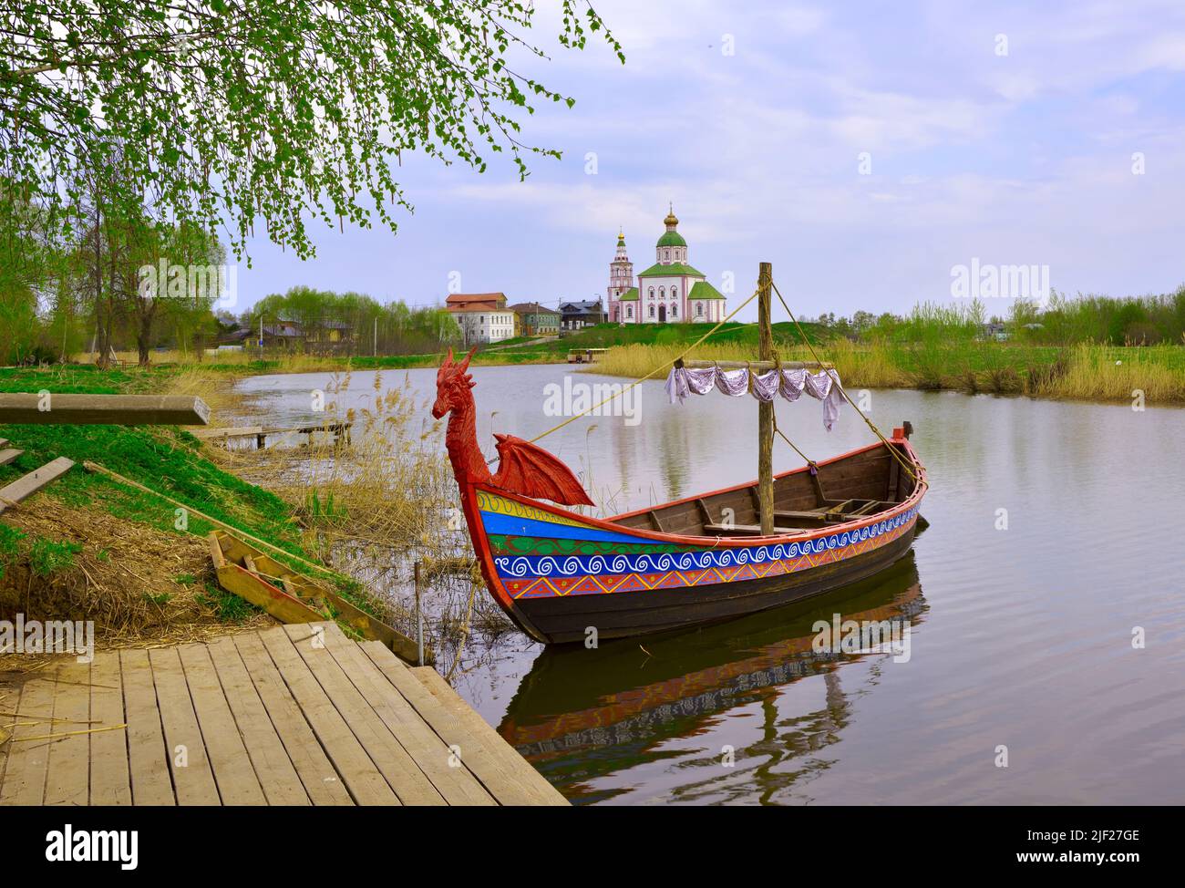 Barca turistica al molo. Drakkar sul fiume, Elia Chiesa all'orizzonte, architettura del XVIII secolo. Suzdal, Russia, 2022 Foto Stock