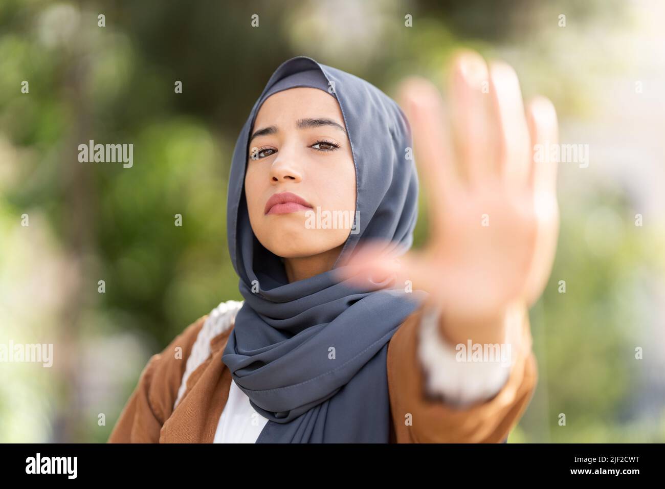 Donna musulmana seria che gesturing si ferma con la mano Foto Stock