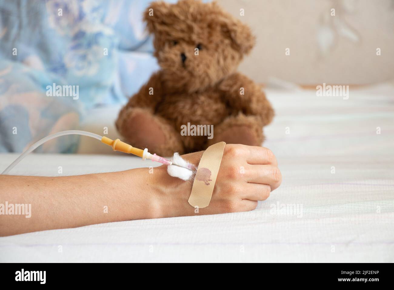 La mano dei bambini con un contagocce sul letto e accanto ad esso si trova un orsacchiotto dei bambini nell'ospedale del reparto, la medicina dei bambini, un bambino malato Foto Stock