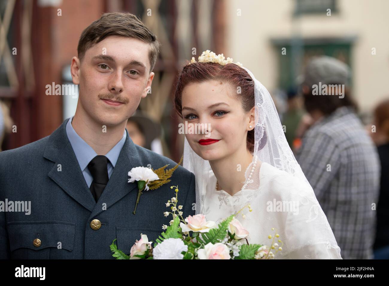 Dudley, regno unito Luglio 16 2016 l'uomo degli sposi appena in uniforme donna in abito sposa che tiene il bouquet isolato dallo sfondo 1940's concetto di tempo di guerra Foto Stock