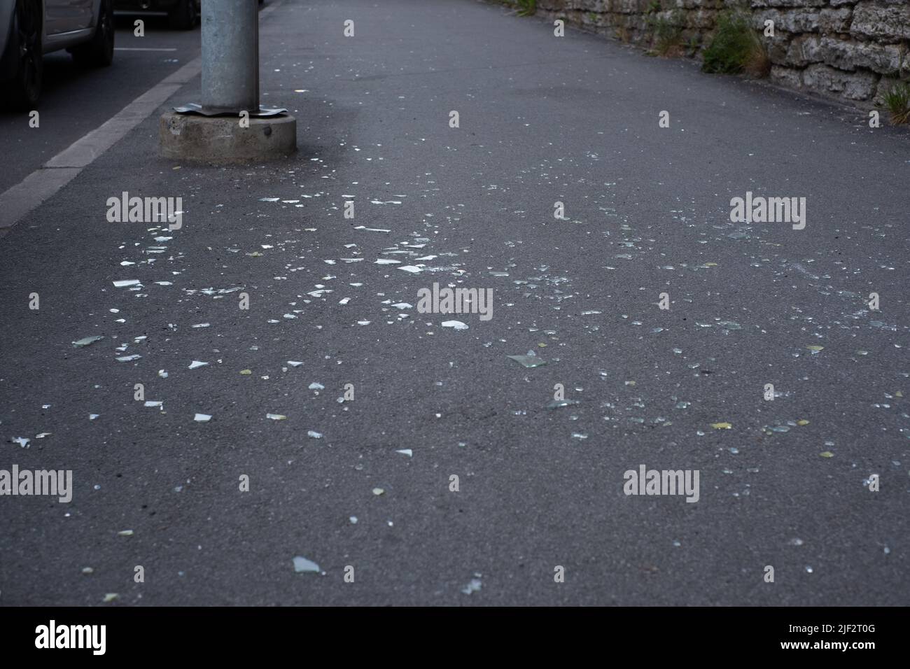 Vetro frantumato su una strada pubblica. Finestra di vetro rotta caduta a terra dall'edificio. Foto Stock