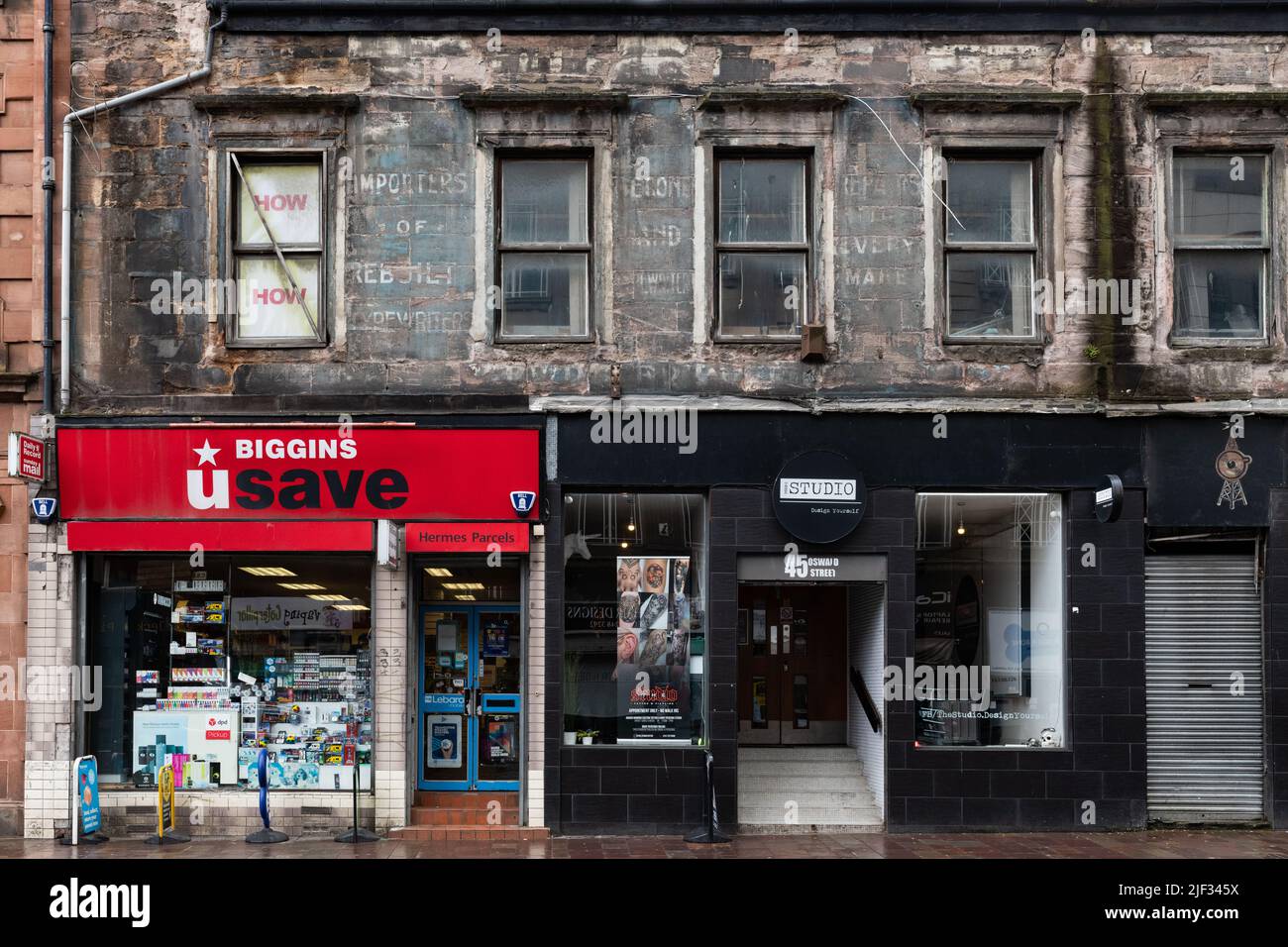 Oswald Street Glasgow - Typewriter Repair Co segno fantasma sopra Biggins u negozio di salvataggio e lo Studio Tattoo e Piercing - Glasgow, Scozia, UK Foto Stock
