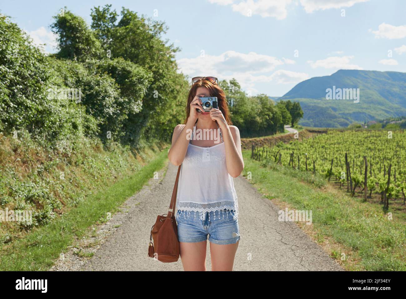 Donna in vacanza da sola fotografando la campagna con la sua fotocamera digitale. Donna accanto a un vigneto che scatta foto con la sua fotocamera digitale. Donna Foto Stock