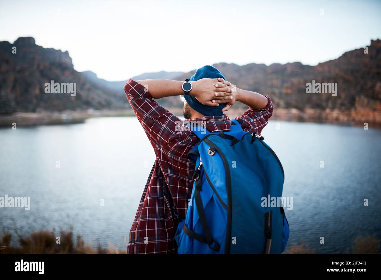 Un uomo escursionista fa una pausa e ammira la vista lago mentre backpacking le montagne Foto Stock
