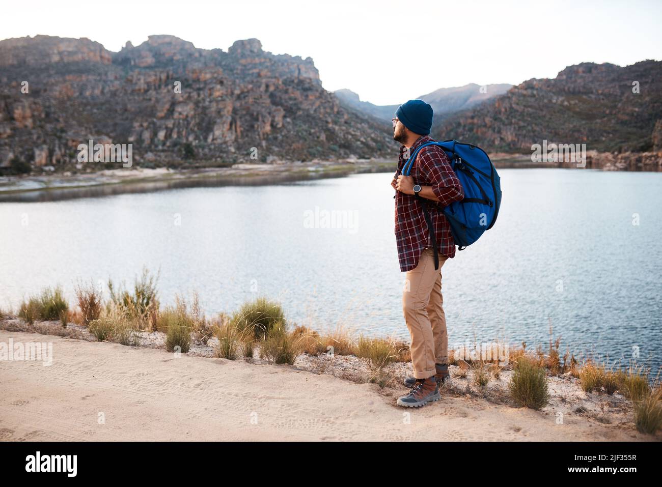 Un zaino in spalla fa una pausa al lago mentre si fa un'escursione in montagna la sera Foto Stock