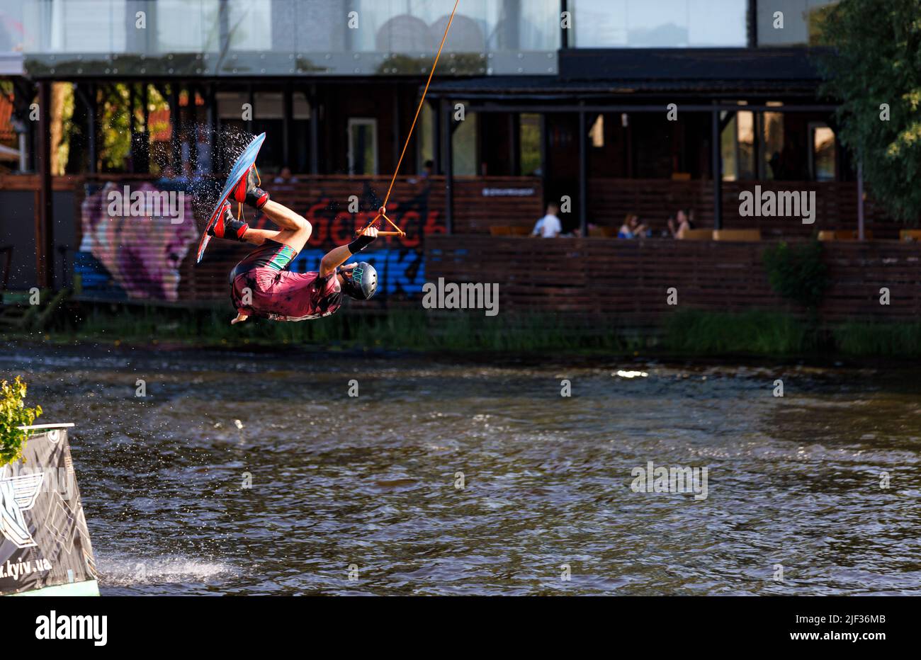 Un wakeboarder fa i somersaults su un bordo dell'acqua sopra la superficie dell'acqua. Sfondo scuro in sfocatura. Spazio di copia. 06.19.1922. Kiev. Ucraina. Foto Stock