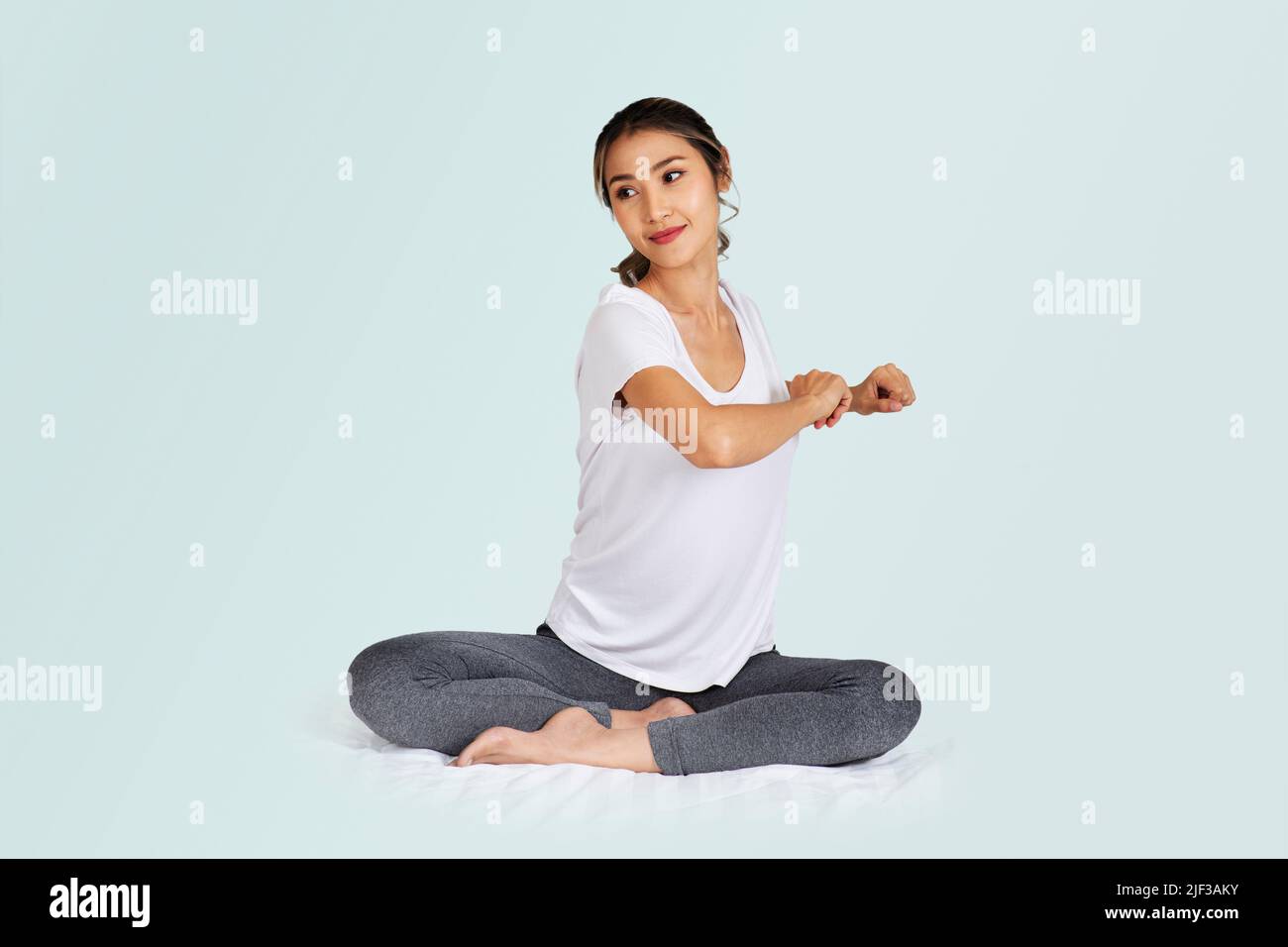 Lo stile di vita della donna seduta sul pavimento che fa si allunga giornaliere per il buon corpo e sano. Foto Stock