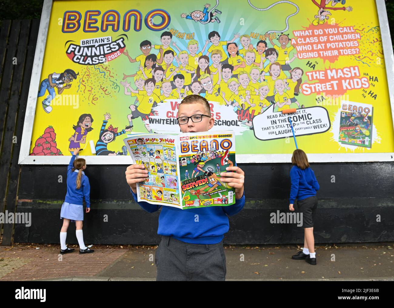 USO EDITORIALE SOLO gli allievi della classe Voyager Year 5 alla Whitehill Junior School svelano un cartellone che illustra il loro scherzo vincente mentre vengono presentati con il trofeo Beano 'Britain's Funniest Class' dal fumettista Danny Pearson, Hertfordshire. Data foto: Mercoledì 29 giugno 2022. La classe si è rivolta alla barzelletta vincente: "Che cosa chiami una classe di bambini che mangiano patate usando le dita dei piedi? - The Mash Street Kids!". La competizione è stata feroce quest'anno con scherzi esilaranti provenienti da tutta la nazione e ricevendo oltre 190.000 voti dal pubblico. L'iniziativa annuale, cr Foto Stock