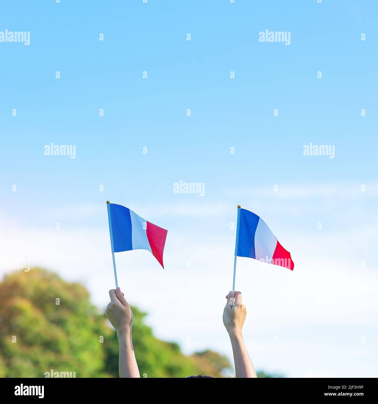 Mano che tiene la bandiera della Francia su sfondo blu cielo. Festa della festa nazionale francese, Bastille Day e felice celebrazione concetti Foto Stock