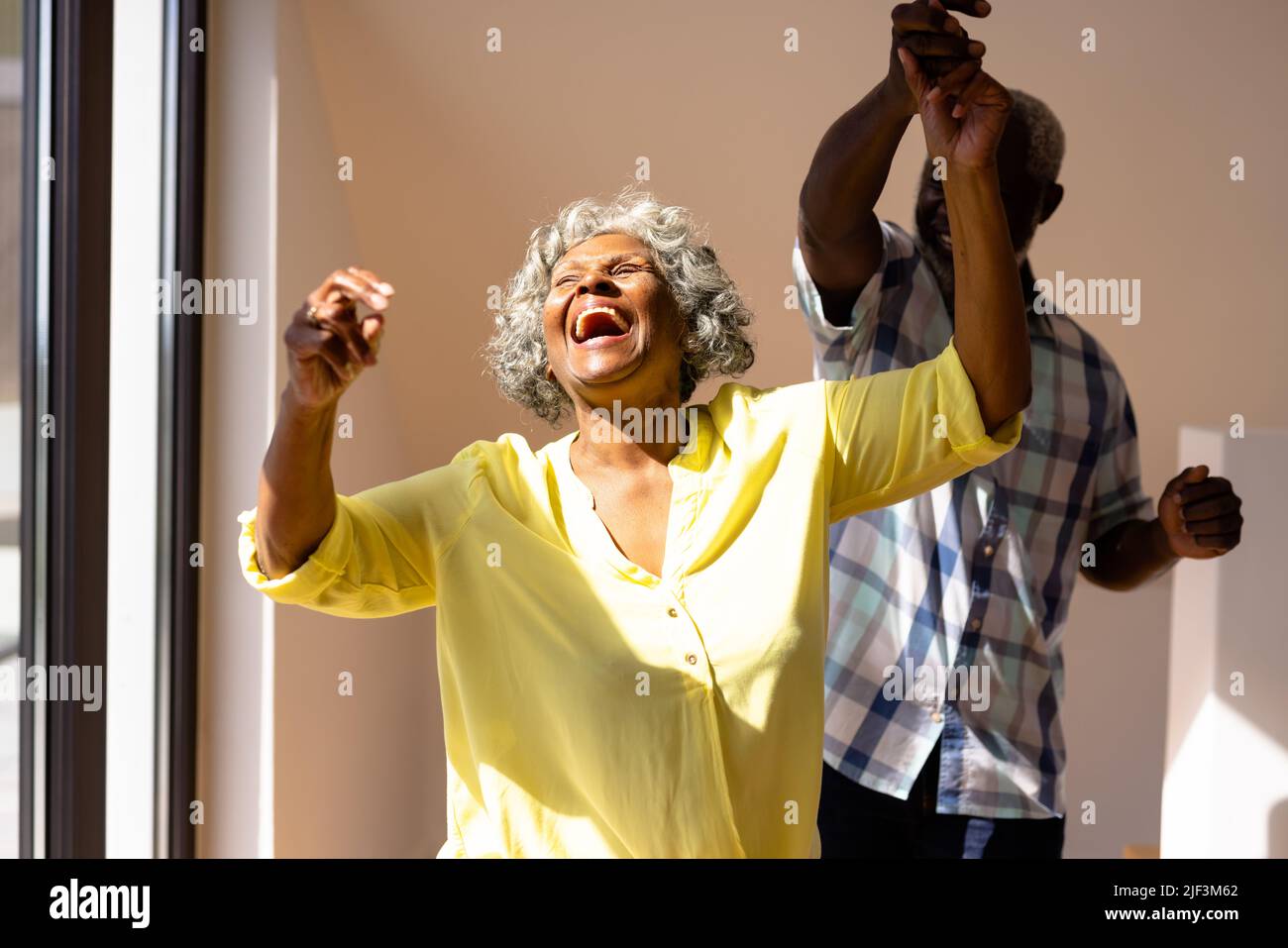 L'uomo anziano africano americano che balla con donna allegra contro il muro in casa di cura Foto Stock