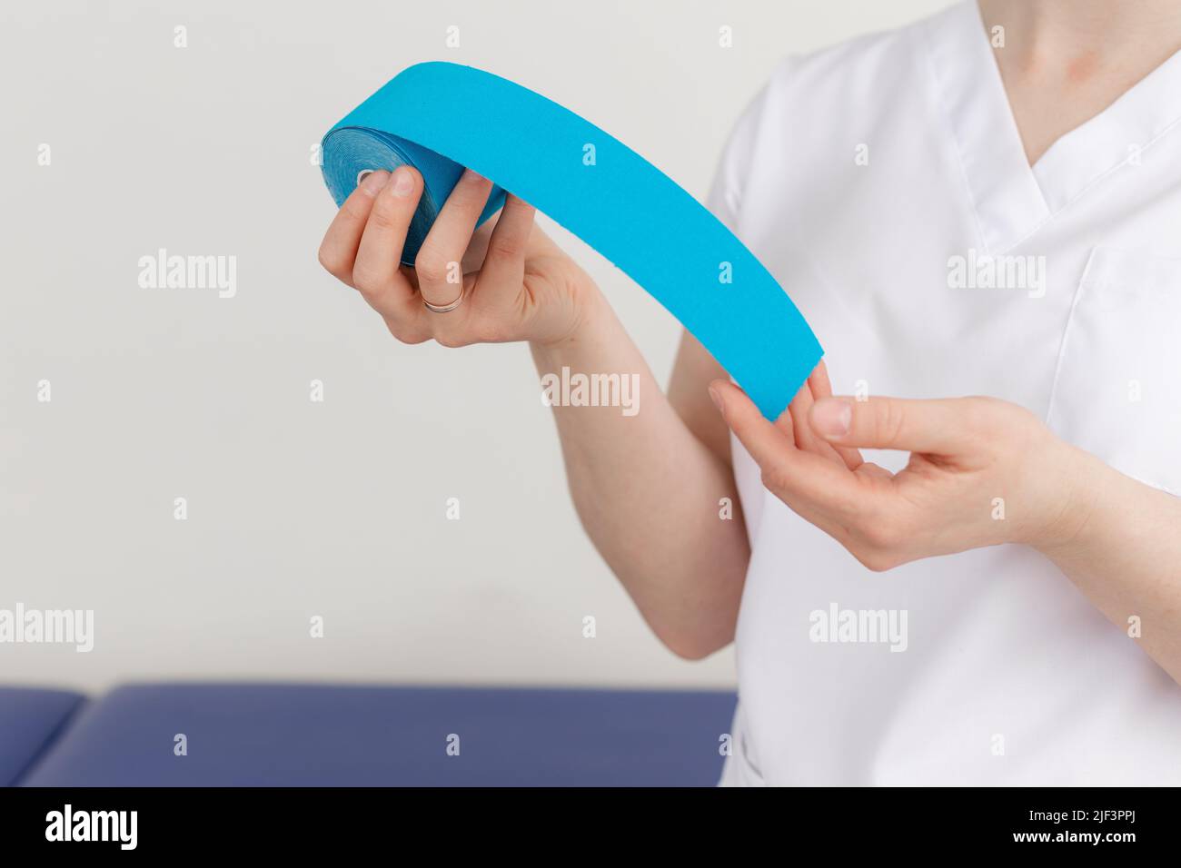 Cropped femmina medico terapista, medico guardare la macchina fotografica, mostrando, pubblicità cinesiologia blu fisiologica nastro. Sport di Lfting Foto Stock