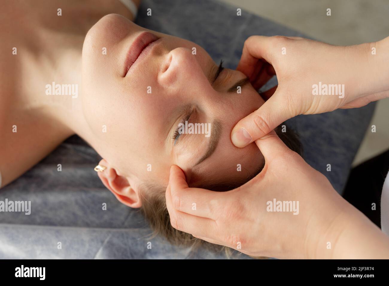 Cropped close up femminile osteopata mani fissare, massaggiando testa paziente, viso. Medicina alternativa. Assistenza sanitaria, relax Foto Stock