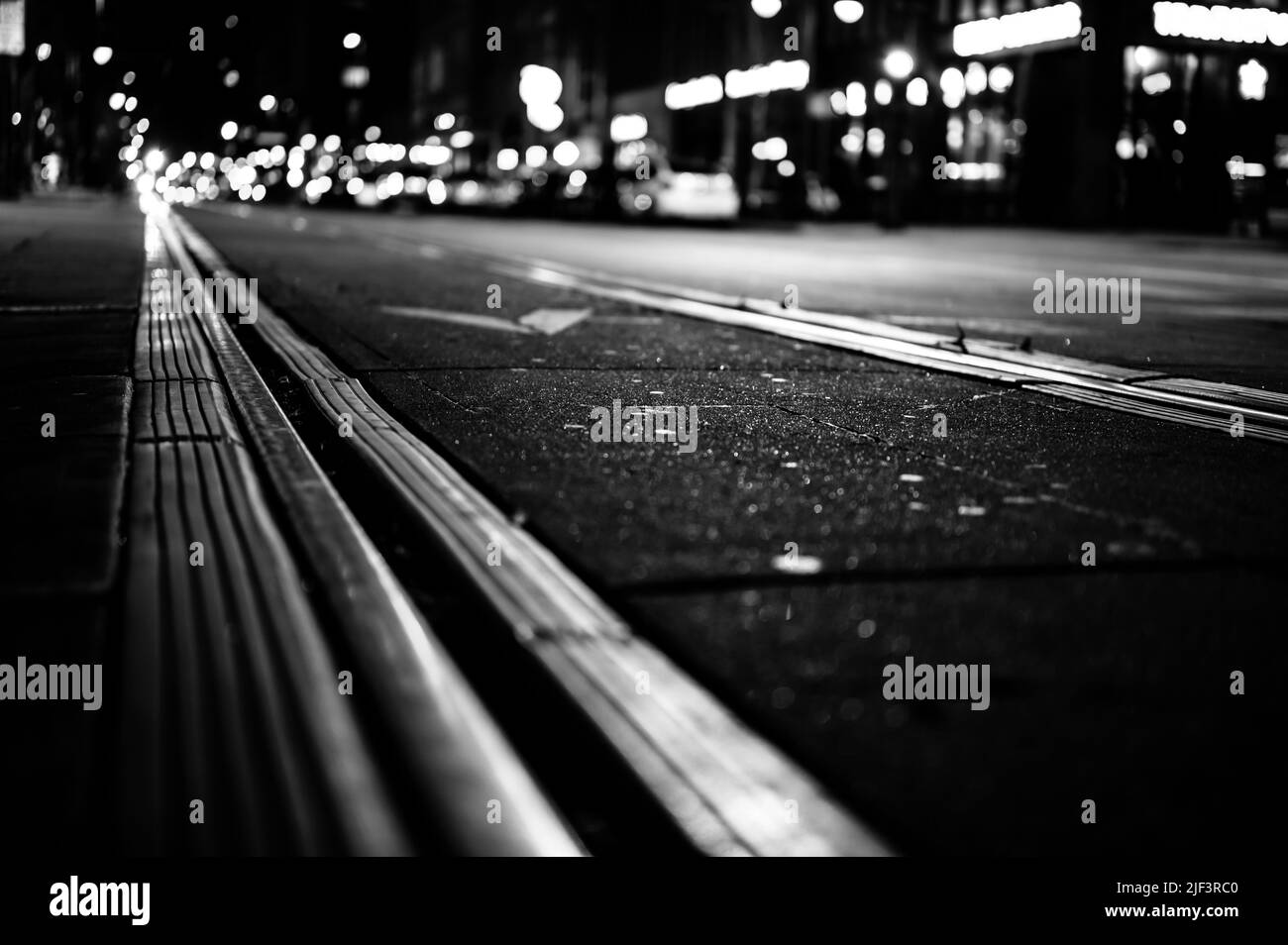 Attenzione selettiva a livello stradale sulle linee ferroviarie del tram di notte a San Diego. Foto Stock