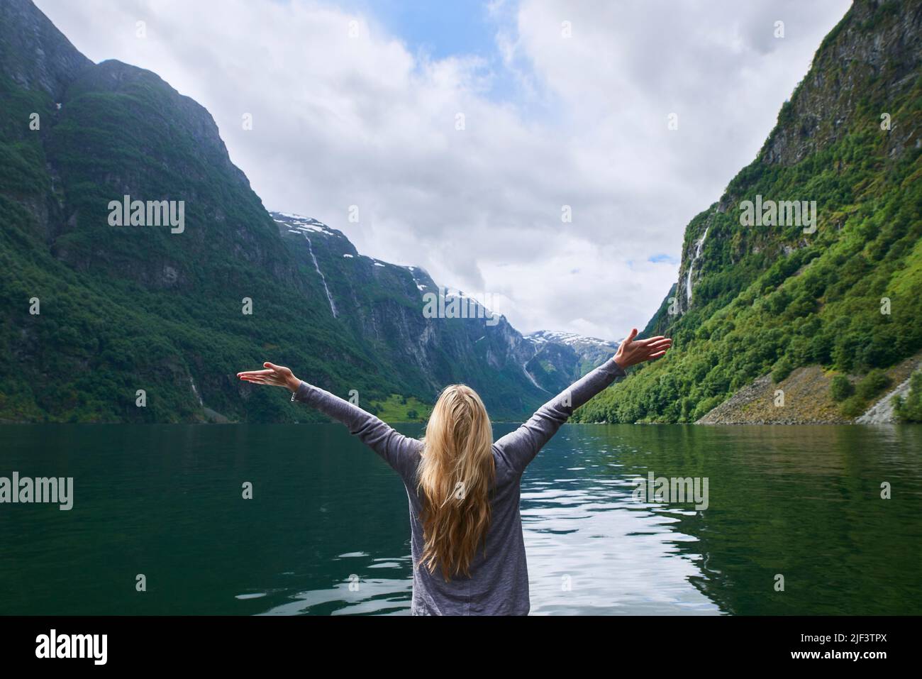 La donna di viaggio avventura celebra le braccia sollevate in vista della maestosa valle glaciale fiordo lago durante l'esplorazione scoprire la bella terra Foto Stock