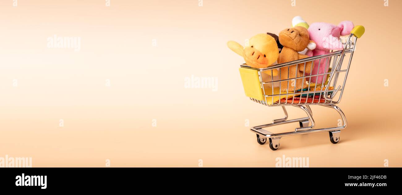 Mini carrello per lo shopping per bambini pieno di morbidi giocattoli per bambini sul banner con spazio per la copia del testo pubblicitario. Foto di alta qualità Foto Stock