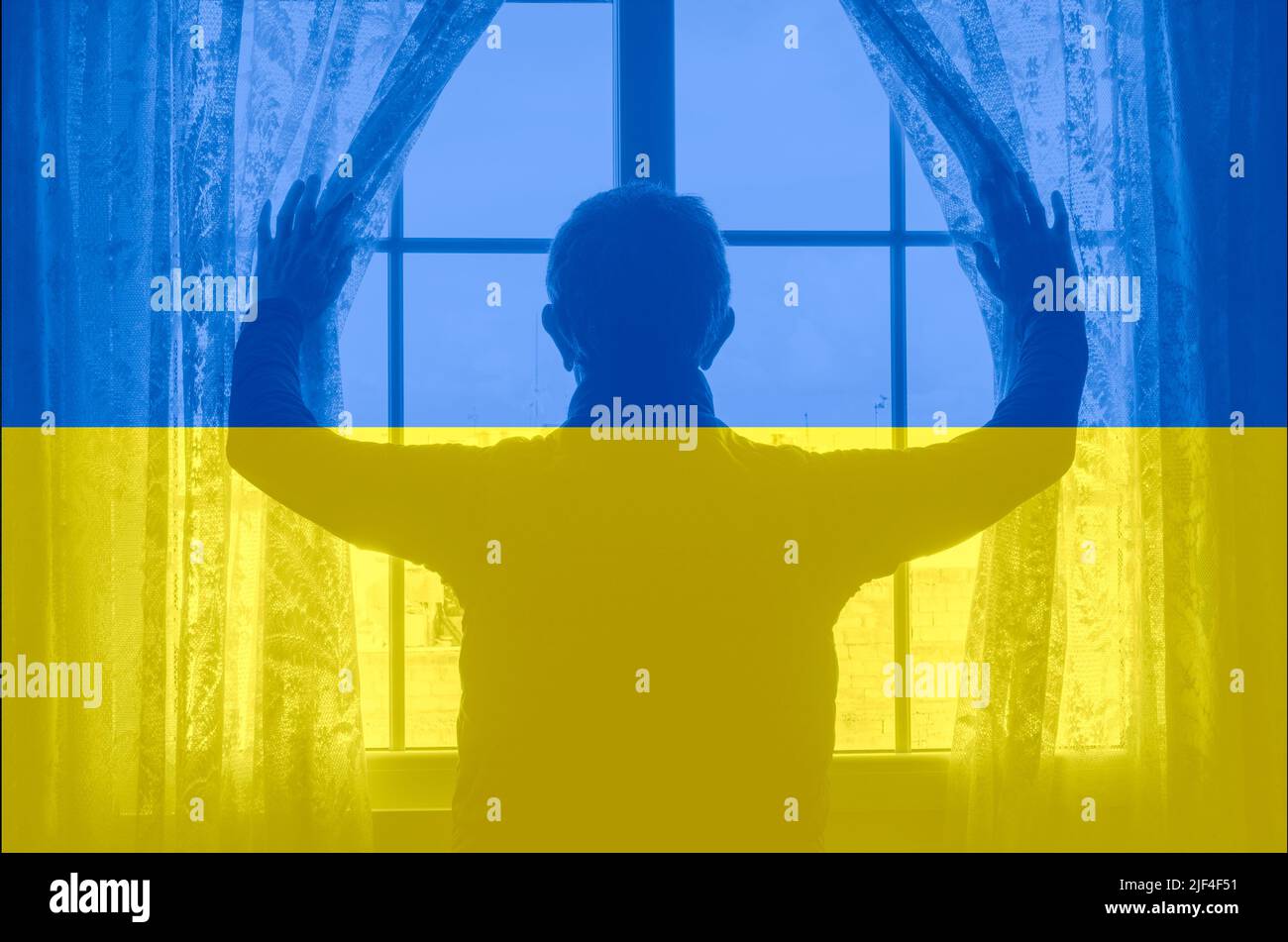 Uomo che guarda fuori dalla finestra con la bandiera dell'Ucraina sovraccaricato. Russia Ucraina guerra, rifugiati, case per ucraina, asilo, PTSD, salute mentale... concetto Foto Stock