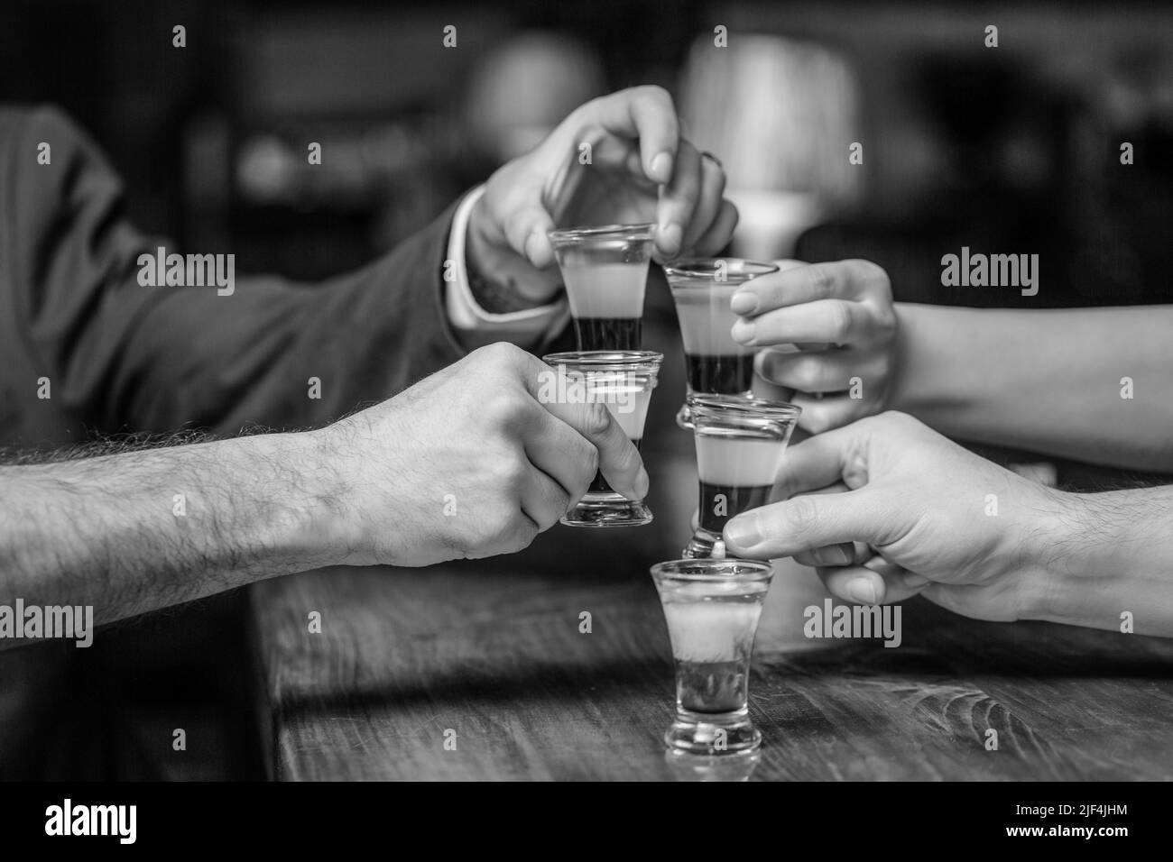 Cocktail al nightclub. Gli amici di gruppo hanno girato i bicchieri di tequila al bar. Bicchieri di palline o liquore a mani maschili. Amici bere shot o liquore. Cinque Foto Stock