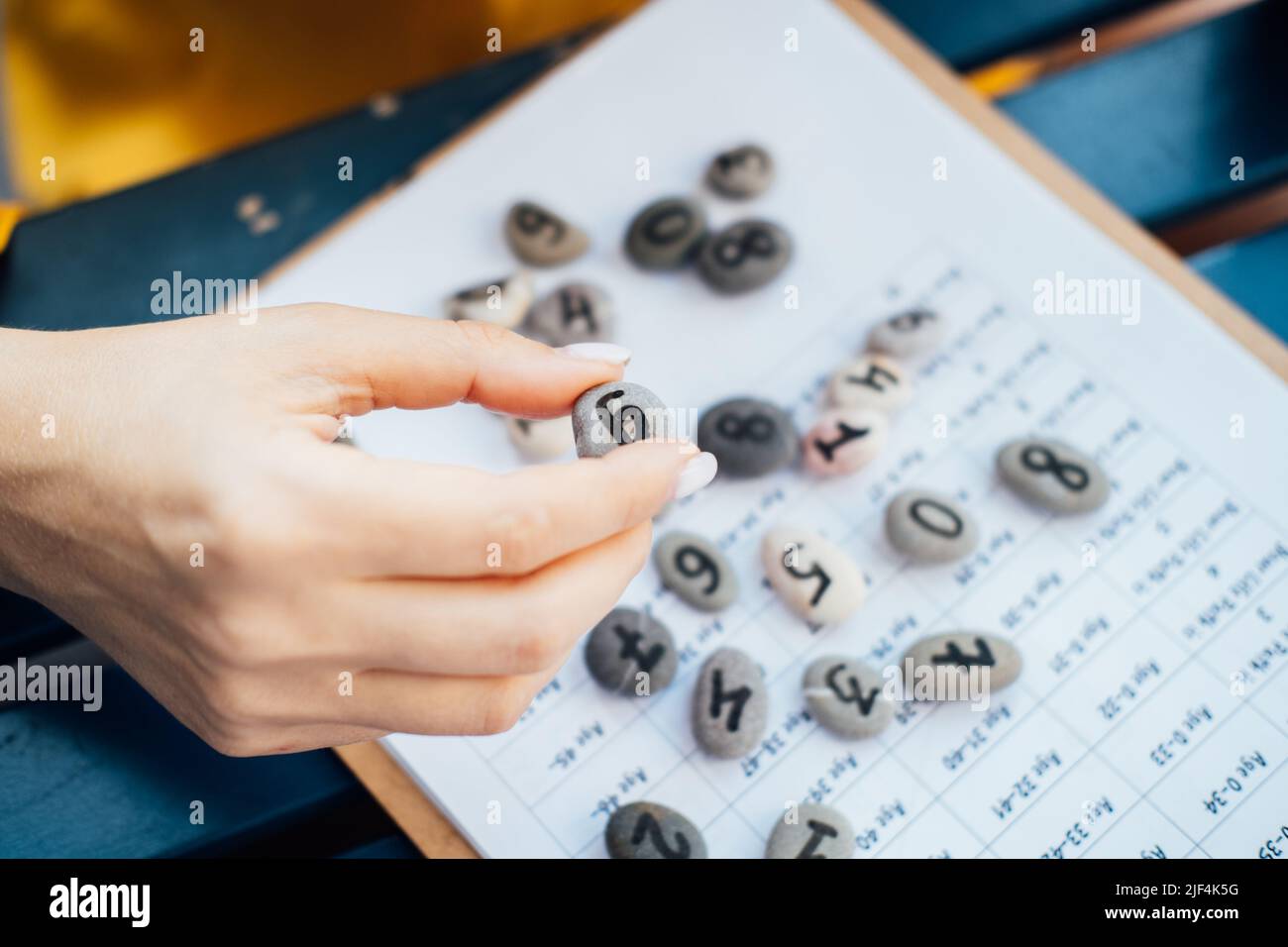 Mano numerologa donna con pietra ciottolosa con numero nove 9. Foto Stock