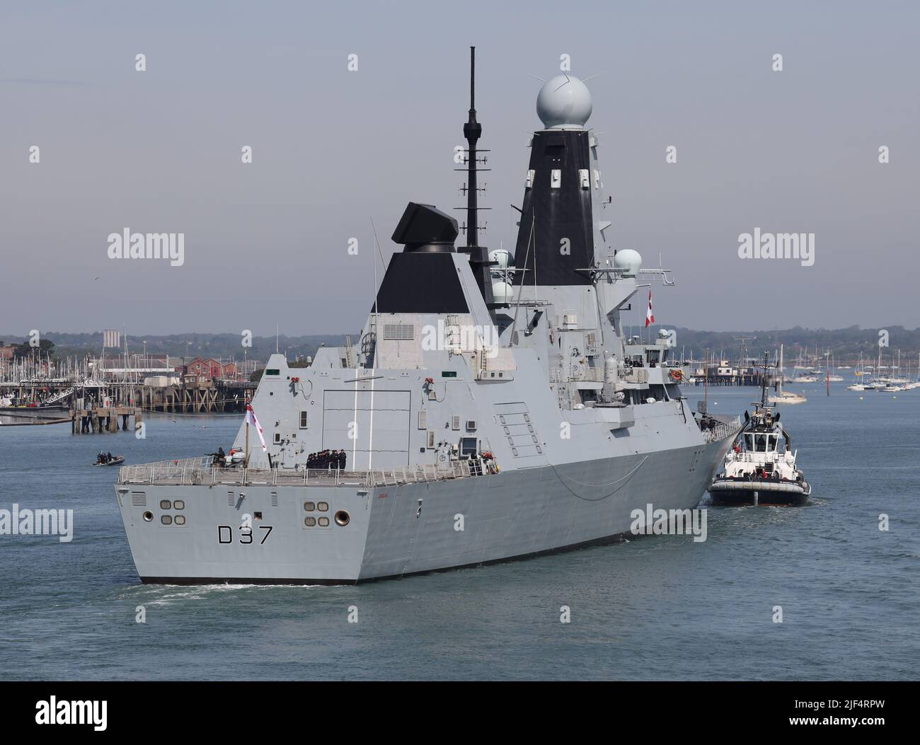 Un rimorchiatore accompagna il cacciatorpediniere Royal Navy Type 45 HMS DUNCAN verso un ormeggio nella base navale Foto Stock