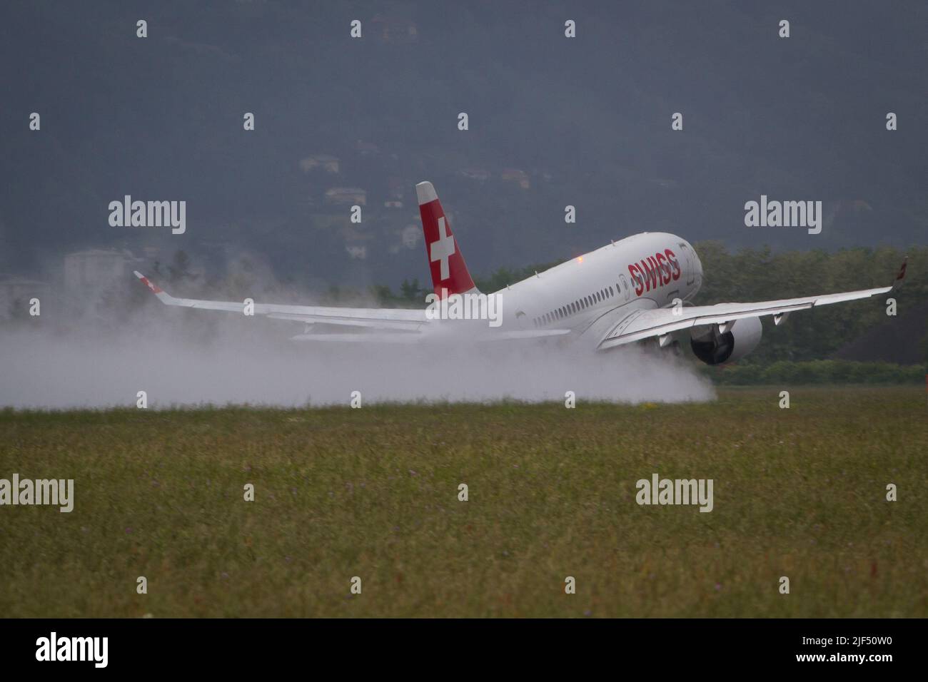 Swiss Airbus A220 con partenza da Graz per un volo a Zurigo da una pista bagnata in una giornata di pioggia Foto Stock