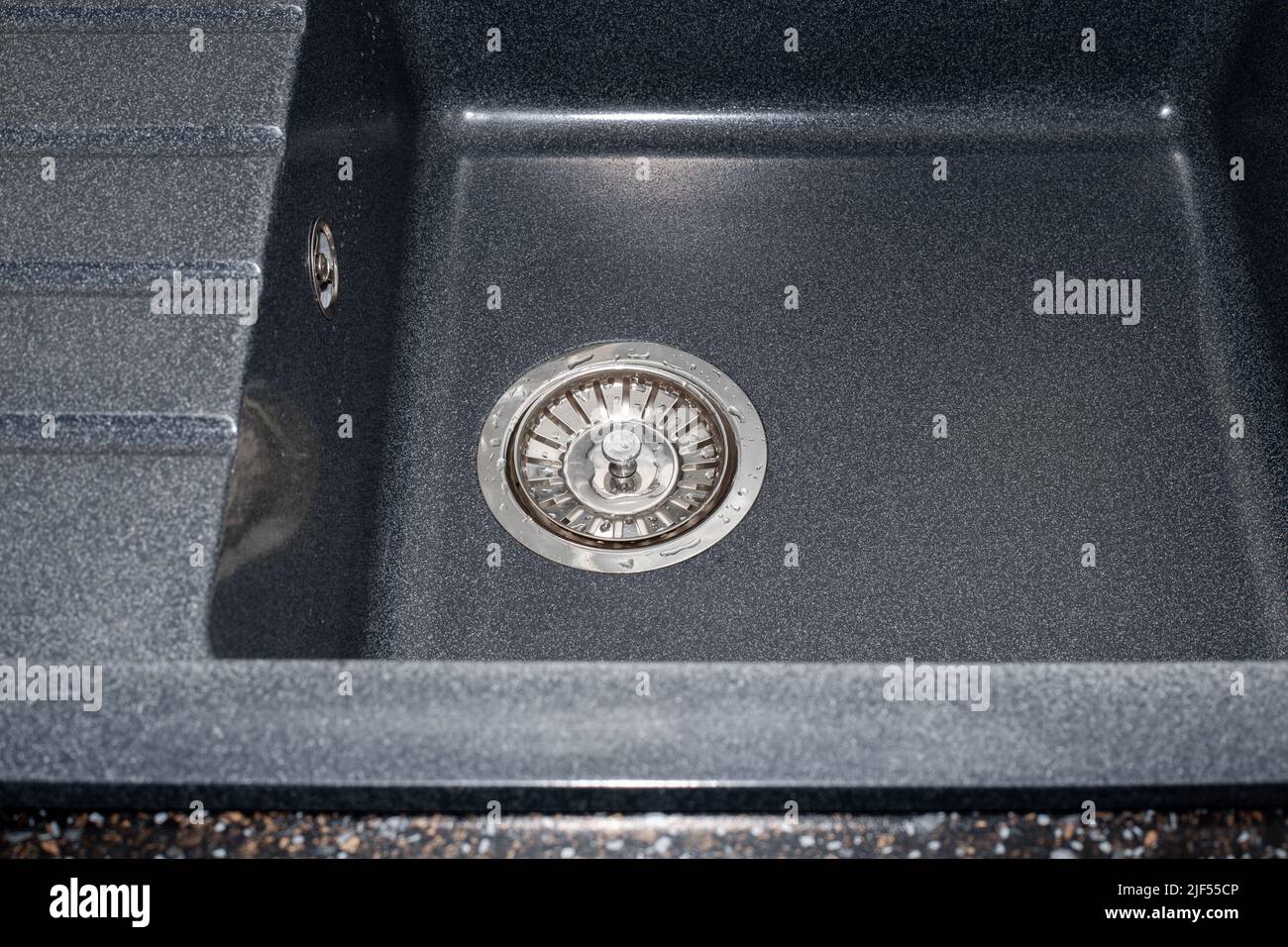 Lavello in pietra artificiale nera con scarico sifone e sistema di traboccamento. Foto Stock