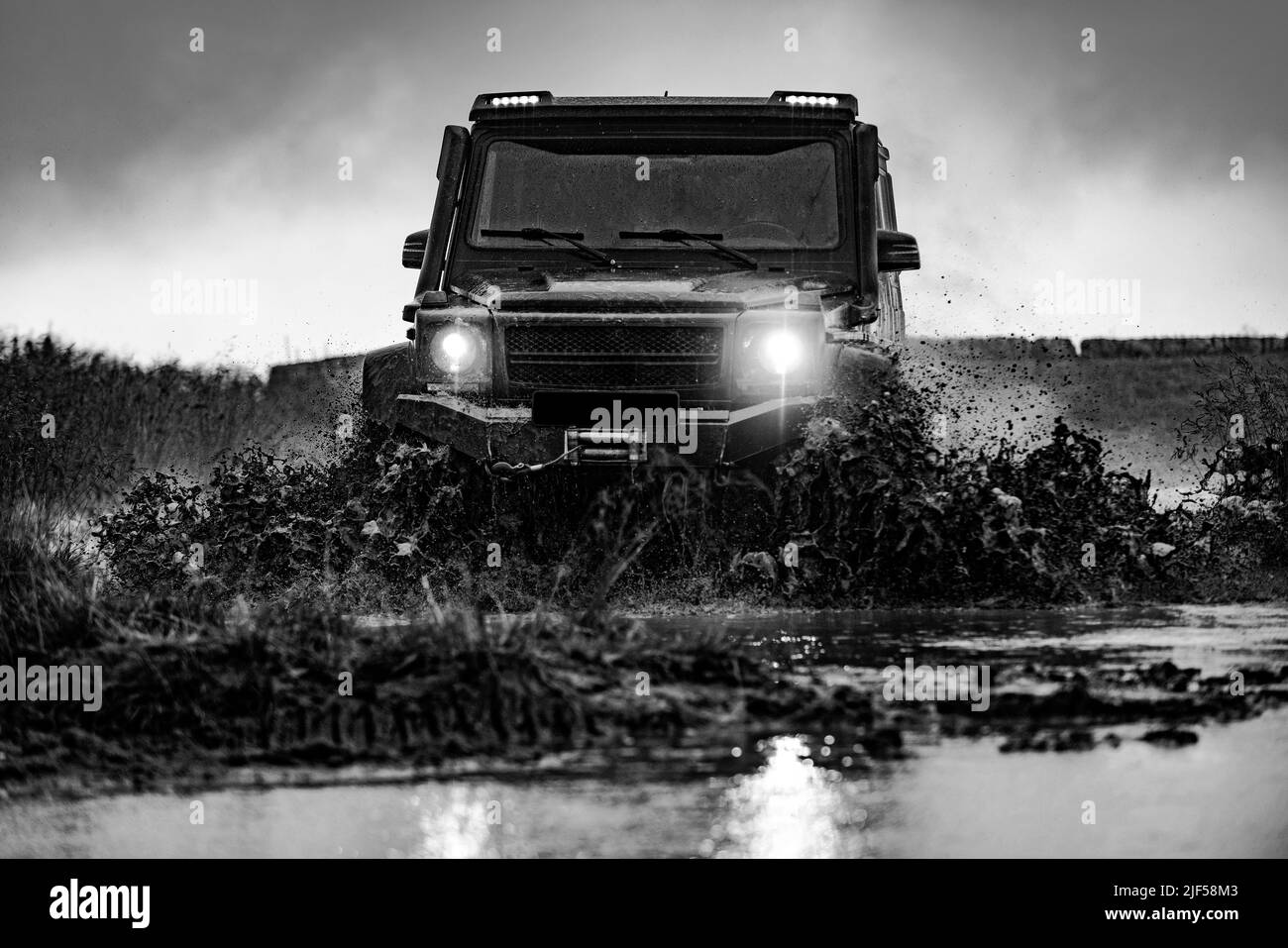 Spruzzi d'acqua nelle corse fuoristrada. Bella natura. Classica vettura 4x4 che attraversa l'acqua con spruzzi su strada fangosa. Auto offroad su strada brutta. Foto Stock