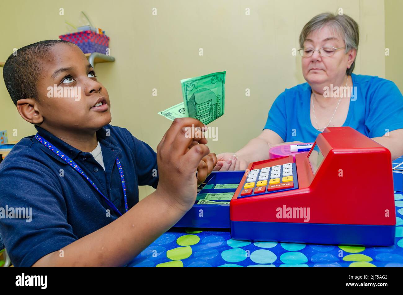 Un tutor volontario aiuta uno studente a fare il cambiamento con un registratore di cassa giocattolo presso un centro di tutoring post-scuola, 28 febbraio 2013, a Columbus, Mississippi. Foto Stock