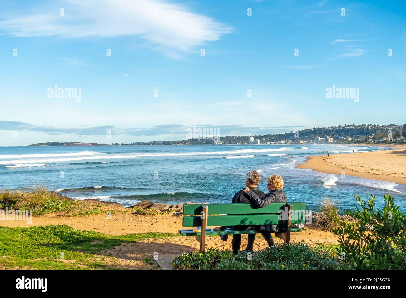 Una coppia in inverno sole che guarda surf a Narrabeen, Sydney Australia. Foto Stock