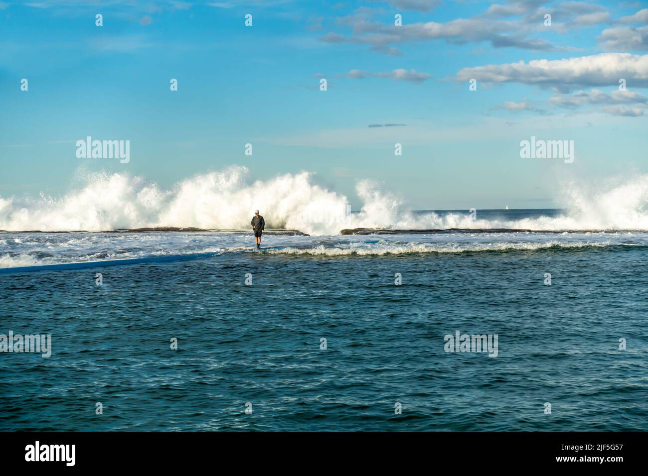 Uomo a piedi lontano dalle onde che si infrangono sulla barriera corallina a Narrabeen Sydney Foto Stock