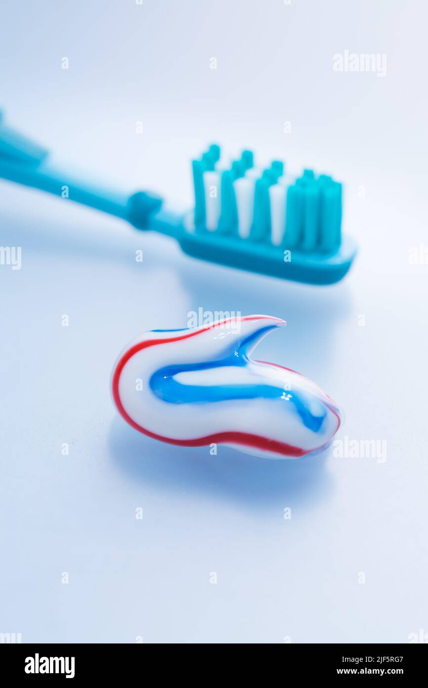 Dentifricio e spazzolino colorati su sfondo blu, concetto di igiene e cura dentale Foto Stock