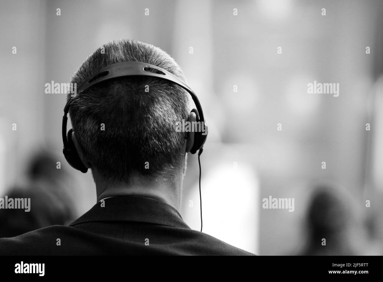 Dettagli di profondità di campo poco profonda (fuoco selettivo) con un uomo caucasico indossando cuffie per traduzione durante un evento internazionale. Foto Stock